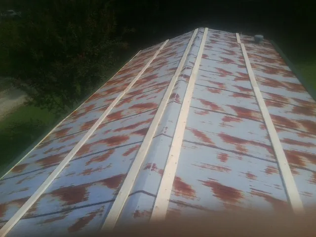 Rusted metal roof panels with new wood purlins before replacement — Storm Damage Roof Repair in David City by Roofing Brothers
