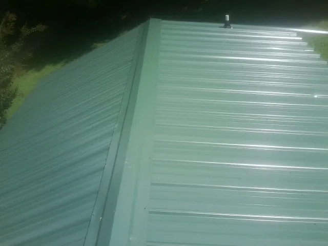 New green metal panels meeting at the ridge of a roof — Flat Roof Repair work by our crew in David City