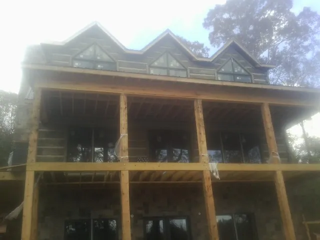 Dormers and porch framing on a large log home under construction — Roof Coating work by our crew in David City