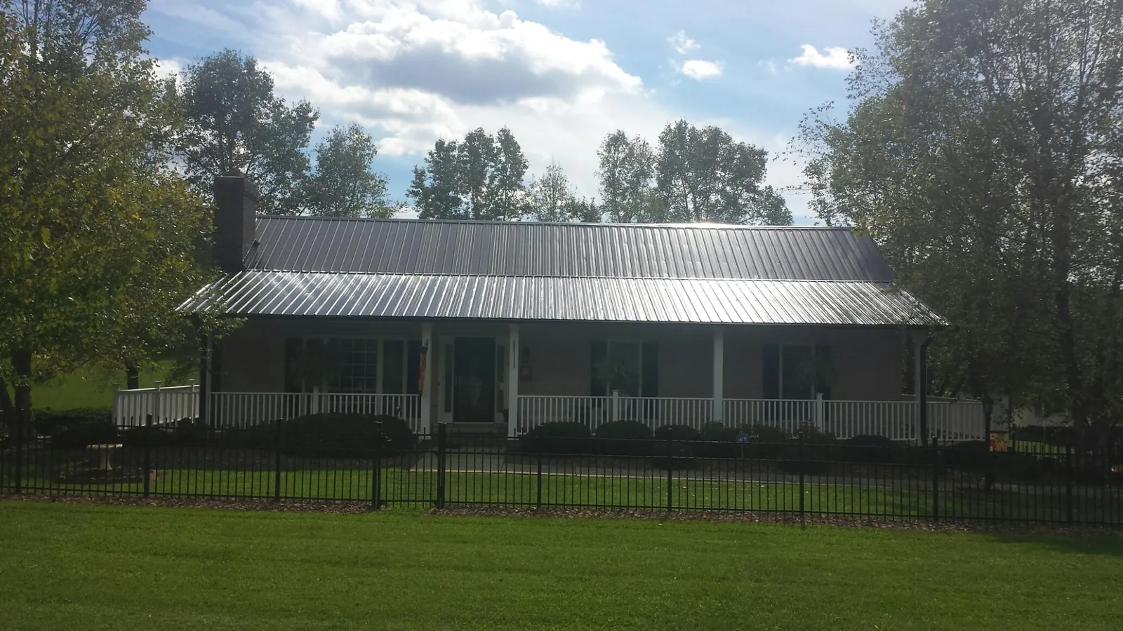 Gray metal roof on a brick ranch with a full width front porch — Gutter Guard Installation work by our crew in David City