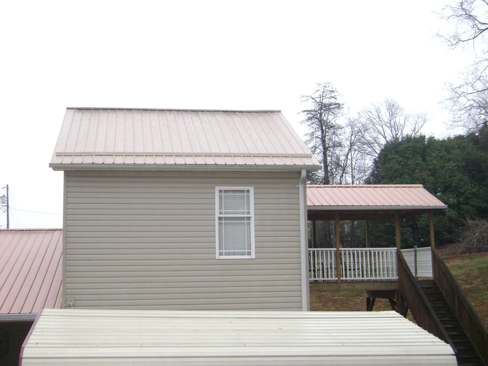 Tan metal roofs on a two story addition and attached porch, from a Roof Replacement job in David City