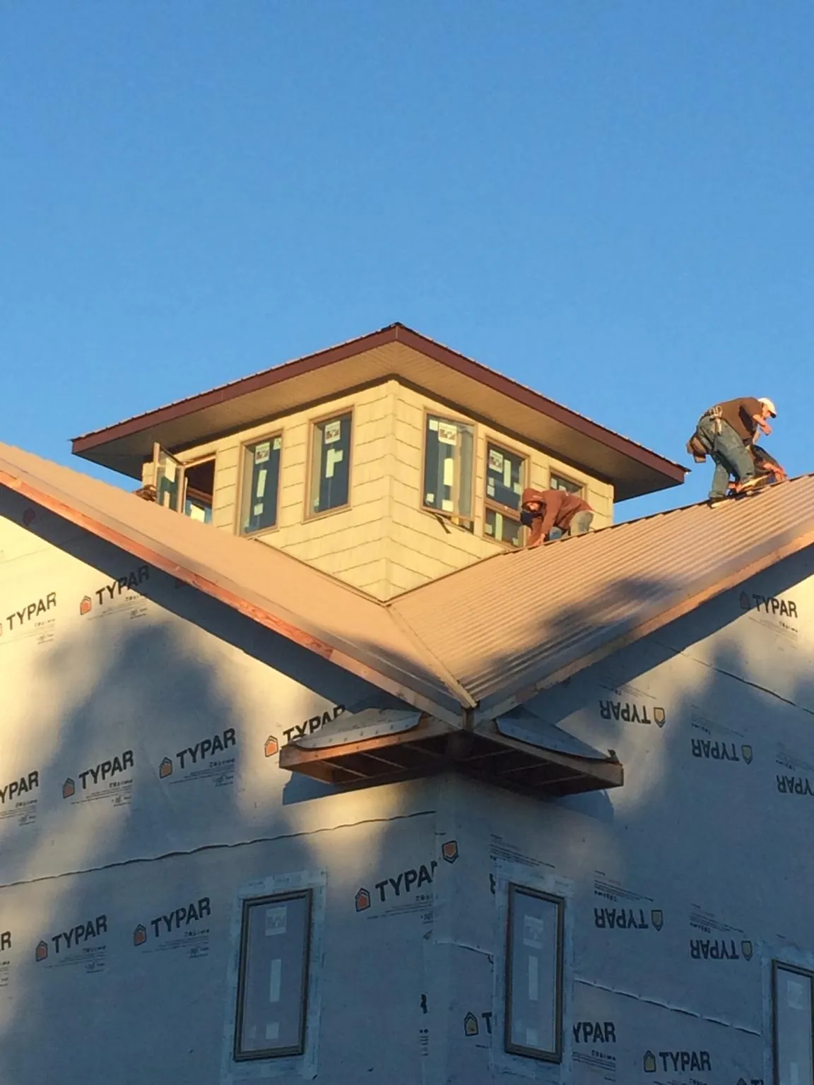 Roofers working around a rooftop cupola on a new metal roof at sunset — Roof Waterproofing in David City by Roofing Brothers